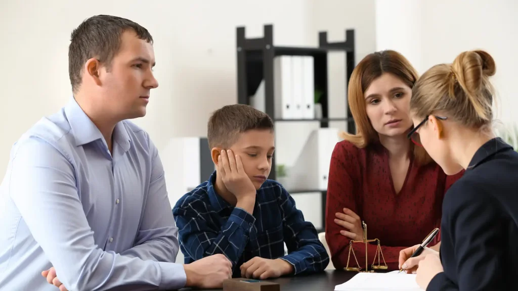 Upset family with child sitting at a table in a legal office.